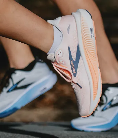 up close view of the orange brooks ghost 18 shoe with the mens blue ghost 18 shoes in the background