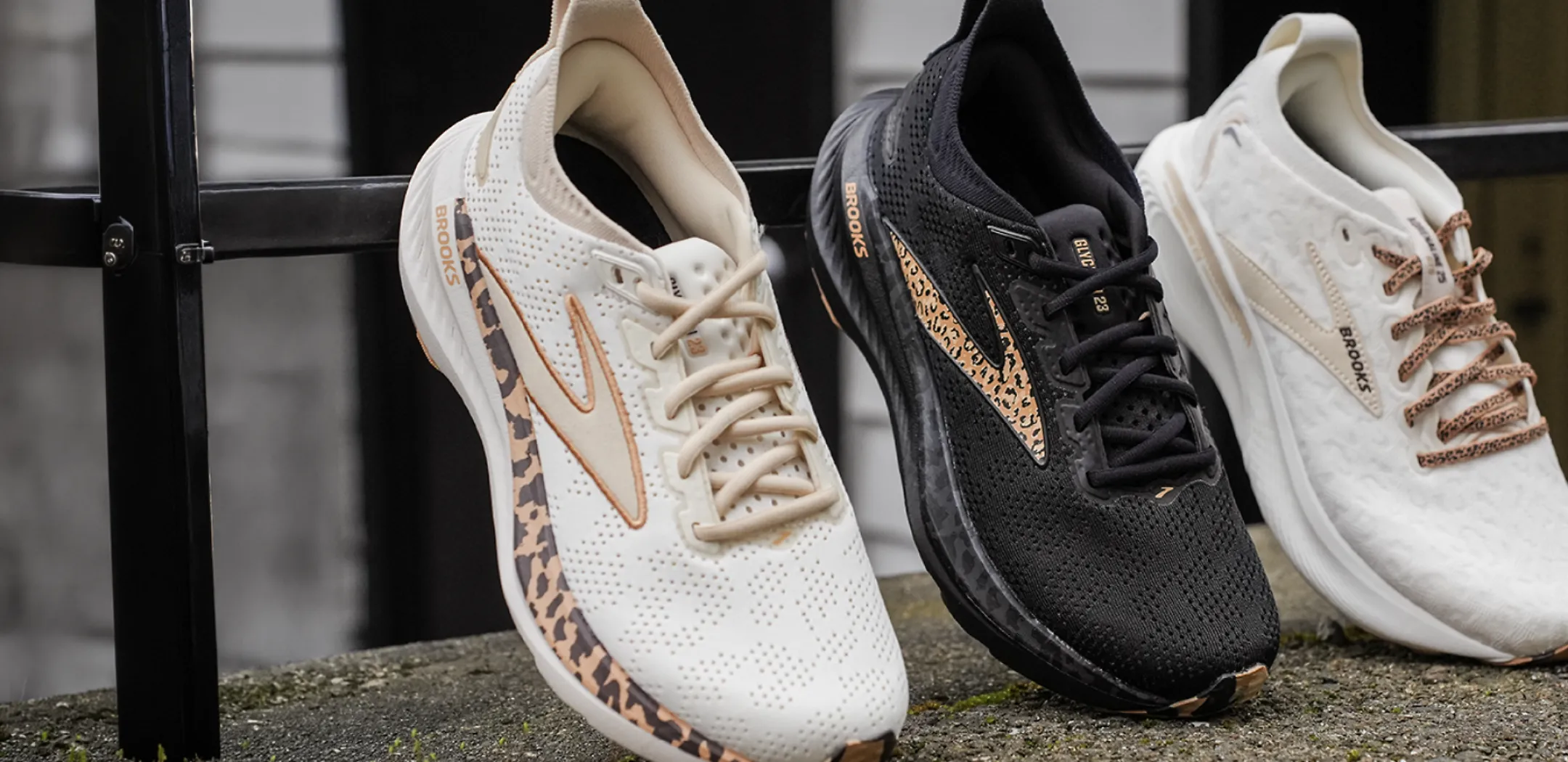 3 brooks shoes propped up against a black metal fence